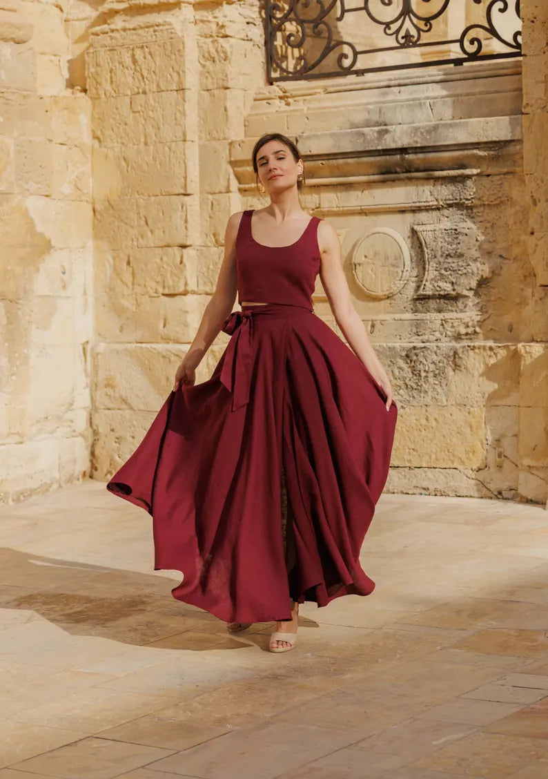 Damen Maxikleid bordeaux mit weitem Rock und Taillengürtel beim Gehen vor Steinarchitektur